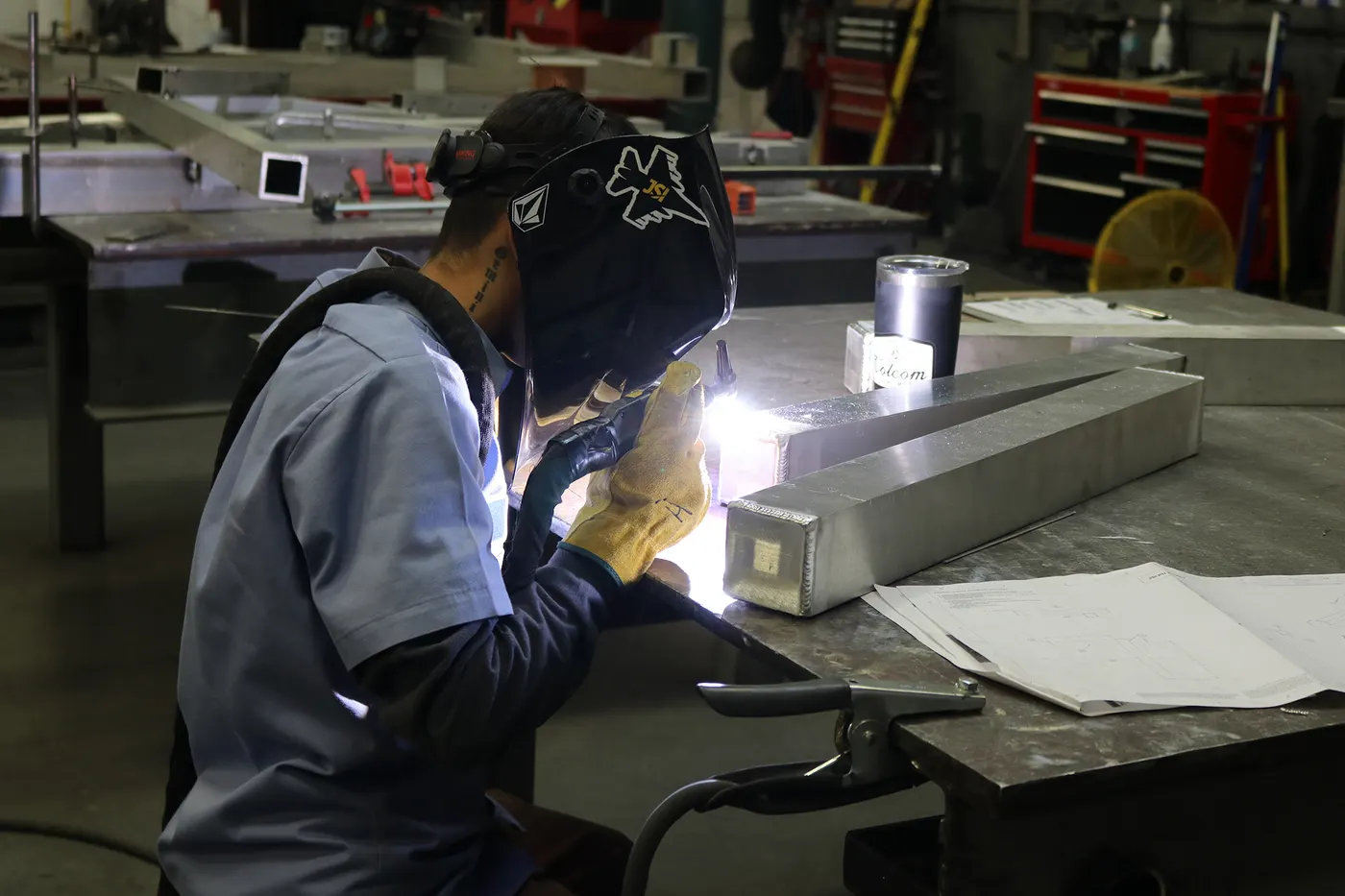 Welder MIG welding an aluminum frame assembly.
