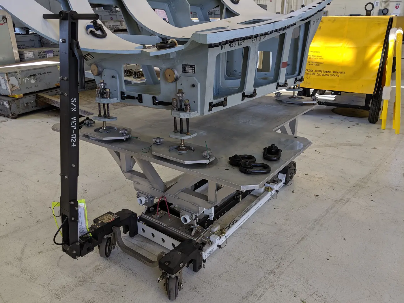 Aircraft structural component supported on a handling cart in the hangar.